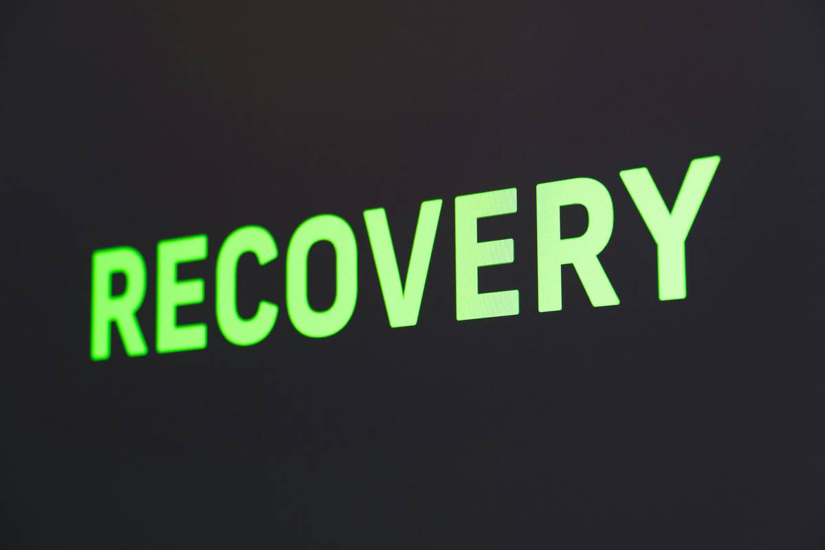 Infographic showing evidence-backed chronic pain recovery tools: resistance bands for graded loading, lacrosse ball for myofascial release, NMES device for muscle activation, and kinesiology tape for proprioceptive feedback